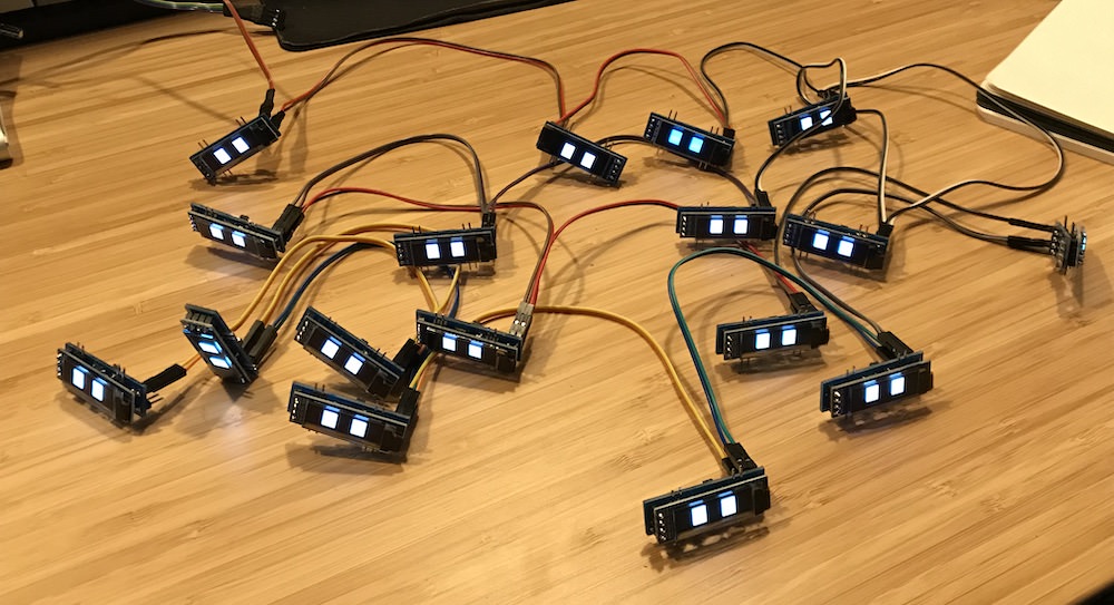 Seventeen small OLED boards wired together into a loose network on a table