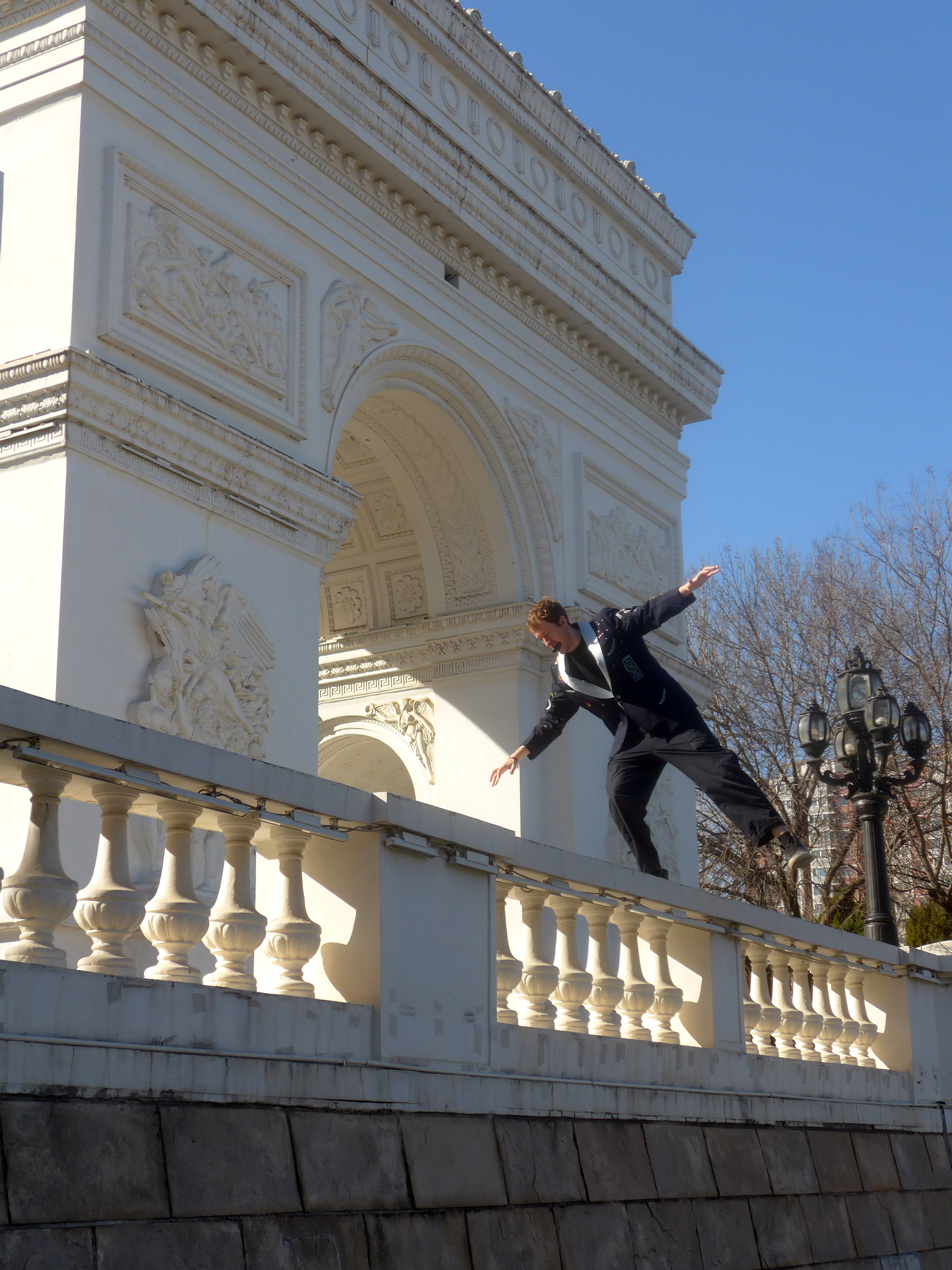 Leaping off a balustrade in the jacket, arms outstretched